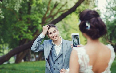 The bride and groom in nature. Wedding day. Bride takes pictures of the groom