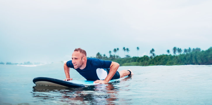 Surfer man floats on surfboard