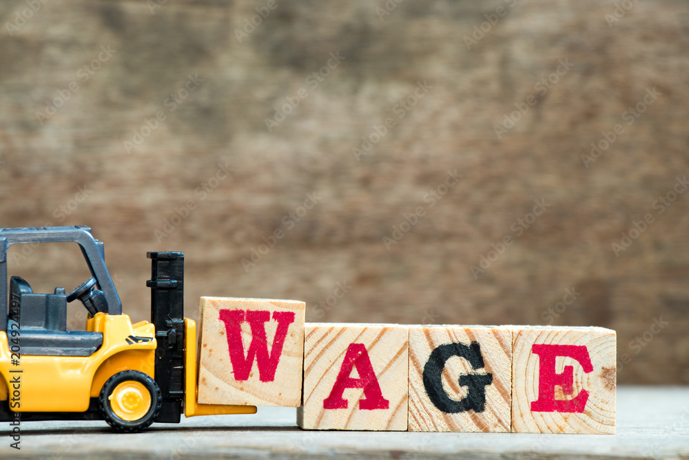 Poster Yellow toy forklift hold letter block w to complete word wage on wood background