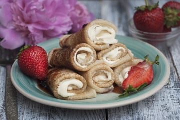 Obraz na płótnie Canvas Sweet Delicious Pancakes Rolled Thin Pancakes with Strawberry Rustic Gray Wooden Board