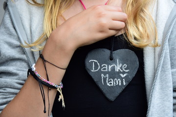 Mädchen sagt mit Herz aus Schiefer danke zum Muttertag