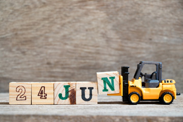 Toy forklift hold block N to complete word 24 jun on wood background (Concept for calendar date in...