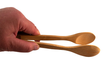 A hand holds a wooden kitchen tongs on a white background.