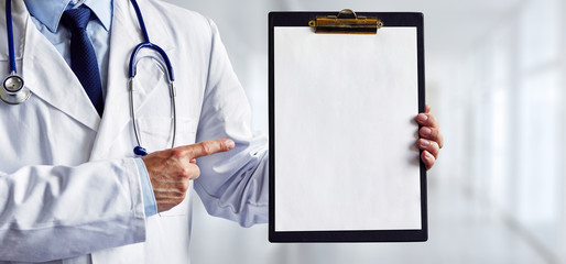 Male doctor pointing to a blank medical clipboard in the hospital