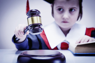 Portrait of serious child girl judge (lawyer) makes a decision. Humorous photo.