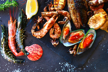 Mediterranean restaurant with a seafood. Beautiful shimps and oysters with some ingredients on a slate desk.