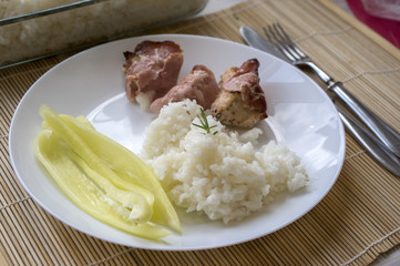 Roasted turkey meat wrapped in ham served with rice on white plate, tasty healthy lunch