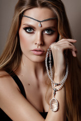 A portrait of a young glamorous woman wearing stylish necklace and pierced earrings.