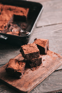 Decadent moist dark chocolate stout beer brownies cut in squares. Black ceramic bakeware. Dark food photography concept