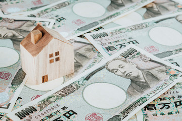 Wooden house model on pile of Japanese yen