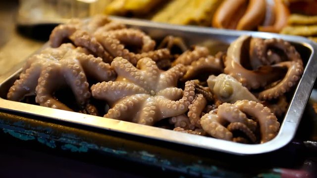 Boiled Octopus. People cooking, selling and buying Asian street Food.