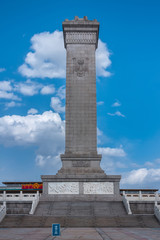 Beijing, China - April 27, 2010: Beige tall square obelisk of war memorial to the People&rsquo;s Heroes at Tiananmen Square against ligh blue sky. Back is facade of National Museum of China.