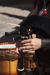 young musician playing the bagpipes on the streets of a city
