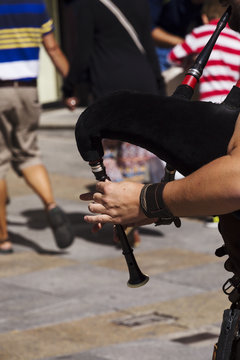 young musician playing the bagpipes on the streets of a city
