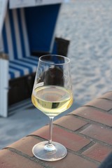 Glas of white wine standing on a brick wall in front of the Westerland beach on the island of Sylt in Germany