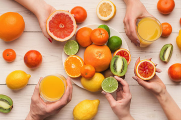 Hands choosing citrus fruits, top view