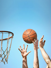Two basketball players throw the ball into the basket with both hands.