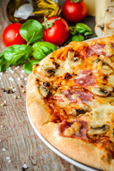 Italian pizza and ingredients on wooden table