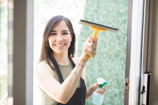 Portrait of attractive young woman cleaning windows