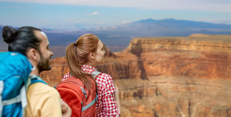 travel, tourism, hike and adventure concept - couple of travelers with backpacks over grand canyon national park background