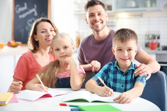 Little children with parents doing homework at home
