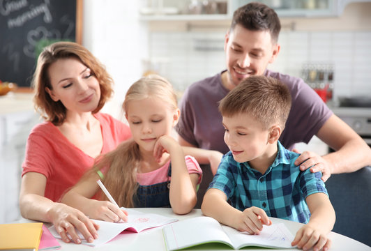 Little children with parents doing homework at home