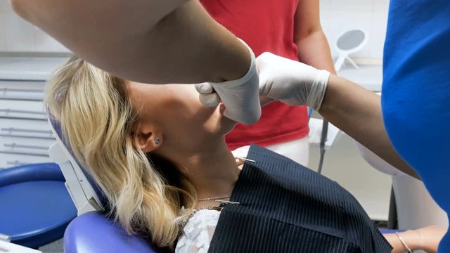 4k footage of dentist inserting special mouth widener in patient's mouth