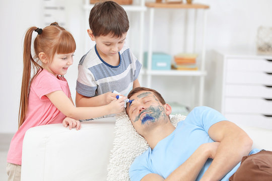 Little children painting their father's face while he sleeping. April fool's day prank