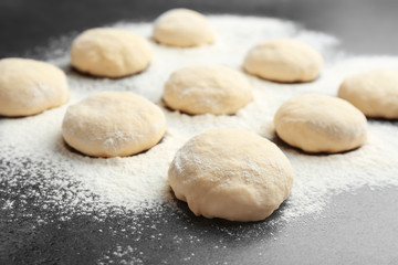 Raw wheat dough and flour on grey table