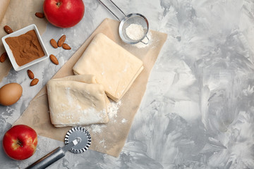 Flat lay composition with raw flaky dough and ingredients on table