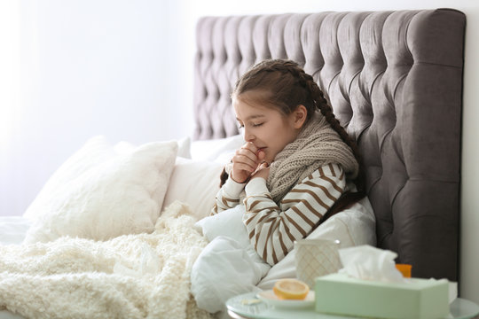 Sick little girl with cough suffering from cold in bed