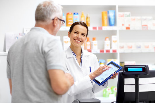 medicine, healthcare and technology concept - happy apothecary and senior male customer with digital prescription on tablet pc computer screen at pharmacy