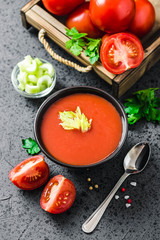 Creamy roasted tomato basil soup in a bowl on dark concrete background. Selective focus, space for text.