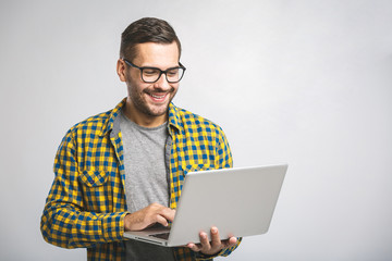Confident business expert. Confident young handsome man in shirt holding laptop and smiling while...