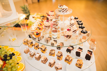 Delicious and tasty dessert table with cupcakes shots at reception closeup