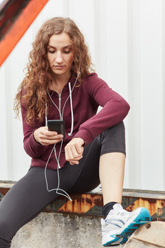 Sportliche Frau mit Smartphone App h&ouml;rt Musik