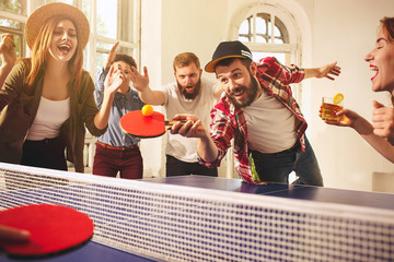 Group of happy young friends playing ping pong table tennis - obrazy, fototapety, plakaty