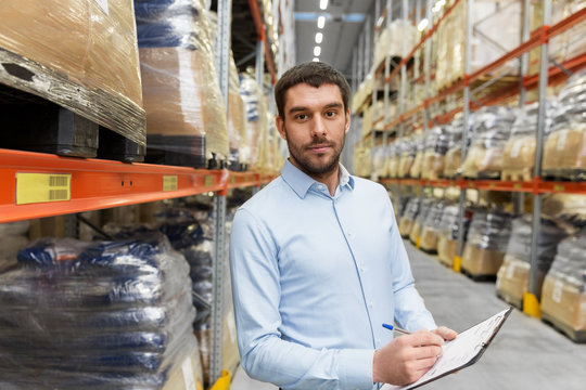 logistic business, shipment and people concept - businessman with clipboard at warehouse