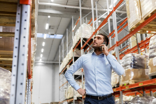 wholesale, logistic business, technology and people concept - businessman calling on smartphone at warehouse