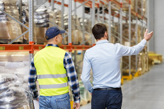 logistic business and people concept - businessman showing warehouse to worker