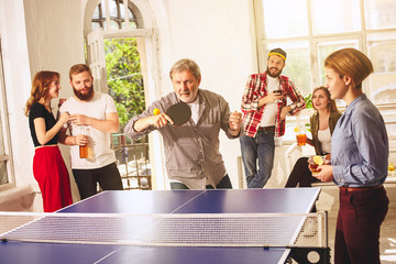 Group of happy young friends playing ping pong table tennis
