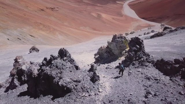Male sky-runner running down summit in a race on the mountain chain of the Atacama desert, 4k. Aerial view of a man descending the summit of a mountain peak.