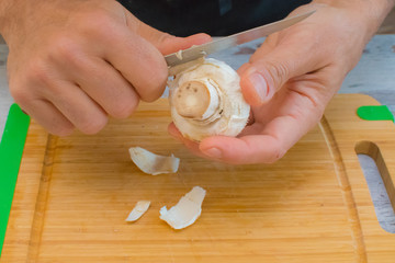 A man is peeling off the outer layers of a white, mushroom