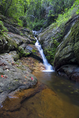 Landscape of small waterfall cascading over a rock with a long exposure