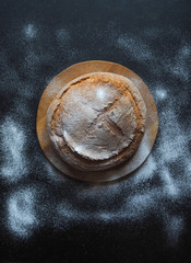 Round baked bread on a black table. Top view. 