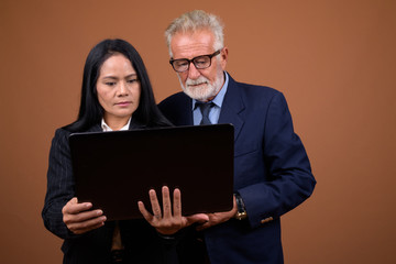 Mature multi-ethnic business couple against brown background