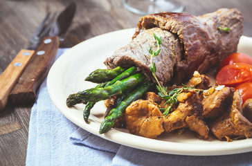 Beef and asparagus roll-ups with mushroom on plate closeup