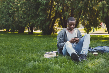 Young man listening to music on grass outdoors