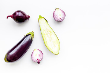 Layout of violet vegetables. Eggplant and red onion on white background top view copy space