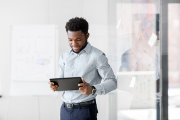 business, people and technology concept - african american businessman with tablet pc computer at...